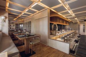 a restaurant with a long bar with tables and chairs at Sini Vie Resort & Spa Seminyak by Ini Vie Hospitality in Seminyak