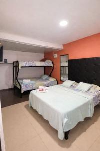 a bedroom with two beds and an orange wall at HOTEL VITRU in Cúcuta