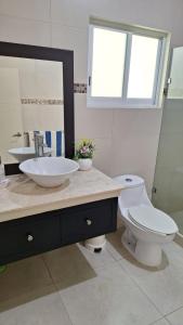 a bathroom with a sink and a toilet and a mirror at Villa Casa blanca Con Alberca privada in Acapulco +15 photos