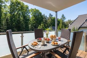 a table with food on a balcony with chairs at Witter Barg - Ferienwohnung mit Sauna in Koserow