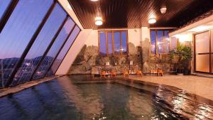 a swimming pool in the middle of a building with windows at Yamaga Onsen Sumi in Yamaga