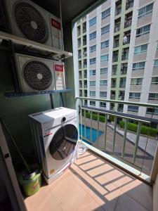 a washer and dryer on a balcony with a building at Modern Grey in Udon Thani