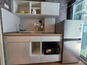 a small kitchen with white cabinets and a refrigerator at Modern Grey in Udon Thani +9 photos