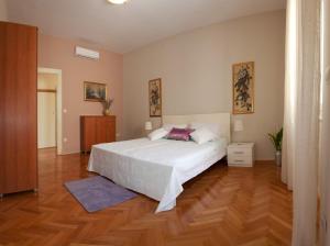 a bedroom with a white bed and a wooden floor at Gianina Apartment in Split