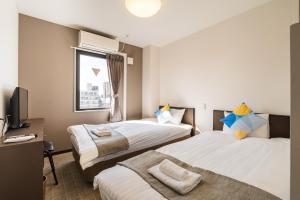ein Hotelzimmer mit zwei Betten und einem Fernseher in der Unterkunft OKINI - Doyanen Hotels in Osaka + 57 Fotos