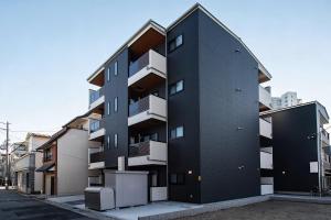 a black building with balconies on a street at New Open! SunLight 岸里 in Osaka