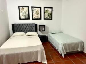 two beds in a room with three pictures on the wall at Casa Mashala in Santa Cruz de Mompox
