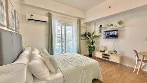 a bedroom with a white bed and a television at Stylish Studio Unit near Airport w Pool and WiFi in Pusok