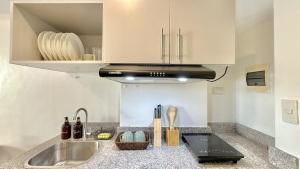 a kitchen with a sink and a stove at Stylish Studio Unit near Airport w Pool and WiFi in Pusok
