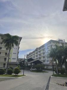 a large building with palm trees in front of it at Stylish Studio Unit near Airport w Pool and WiFi in Pusok