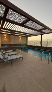 a large swimming pool with benches at Nizwa Inn - نزوى إن in Nizwa