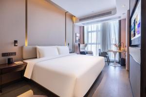 a hotel room with a large white bed and a desk at Atour Hotel Hefei Yaohai Heping Road in Hefei +28 photos