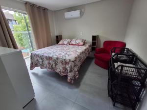 a bedroom with a bed and a red chair at Apartamento novo - 2 Quartos Casal até 4 pessoas - Centro - Santa Rosa - RS in Santa Rosa