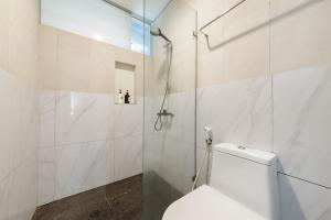 a bathroom with a toilet and a glass shower at Urbanview Hotel The Lodge Karawaci in Tangerang +35 photos