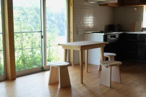 a kitchen with a wooden table and two stools at Lotus Retreat ロータスリトリート 高知空港から車で30分 山のふもとの一棟貸しコテージ in Kami