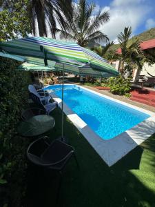 a swimming pool with chairs and an umbrella next to it at Hostal White beach in Paraguchi