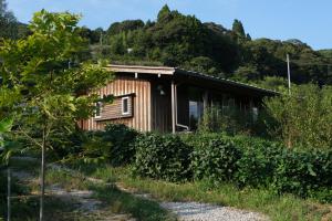 a wooden house with a hill in the background at Lotus Retreat ロータスリトリート 高知空港から車で30分 山のふもとの一棟貸しコテージ in Kami