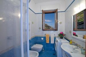 a blue and white bathroom with a toilet and a sink at Calipso Residence in Furore +65 photos