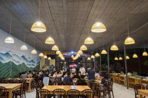 a group of people sitting at tables in a restaurant at Tomato Villa & Restaurant in Da Lat