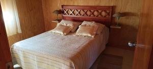 a bed in a bedroom with two pillows on it at Cabaña La Ondina in Melipeuco