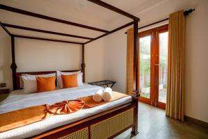 a bedroom with a large bed with orange pillows at 100Steps Mirissa in Mirissa +72 photos