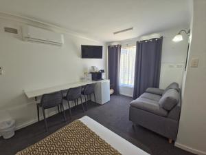 a room with a bed and a couch and a kitchen at Taree Lodge Motel in Taree