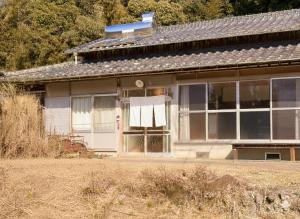 a house with a white curtain on the window at 古民家ステイshinonome inn in Kitsuki
