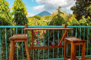 two wooden stools sitting on a fence with flowers at Hostal Edén in Moyogalpa