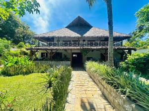 a house with a thatched roof and a pathway at Bungalow du Lagon in Ambaro