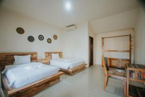 a bedroom with two beds and a table and a chair at Tiny House Nusa Lembongan in Nusa Lembongan