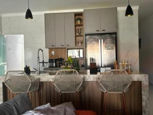 a kitchen with white cabinets and a counter with chairs at Casa Cristã Familiar JR in Paracuru
