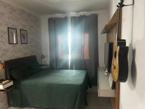 a bedroom with a green bed and a guitar at Casa Cristã Familiar JR in Paracuru