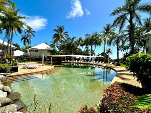 a pool at a resort with palm trees at The Beachfront in Trinity Beach