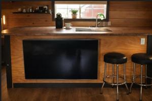a large television in a kitchen with a sink and stools at Charming "Melrose Place" w Year-Round Heated Pool, Deck & Grill in Victoria