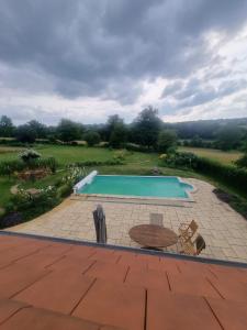 a swimming pool with a table and a patio at Parfums des peintres proche Crozant - Chambres d'hôtes in Villard