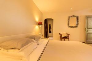 a bedroom with a white bed with a mirror and a chair at La marquette in Montrabé