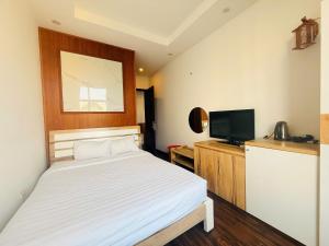 a bedroom with a bed and a flat screen tv at Hoa Viên Hotel in Hòa Ðình