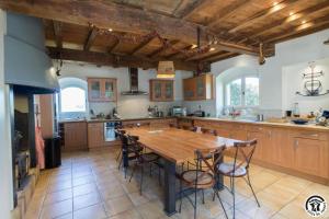 a large kitchen with a wooden table and chairs at La ferme in Ponlat-Taillebourg