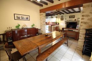 a dining room with a wooden table and a kitchen at Le monteil in Arnac-la-Poste