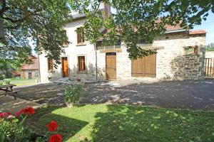 a stone house with a yard with flowers in front of it at Le monteil in Arnac-la-Poste