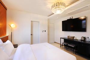 ein Schlafzimmer mit einem Bett und einem Schreibtisch mit Fernseher in der Unterkunft 호텔 더블랙 in Hwangsan-do