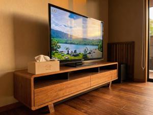 a flat screen tv sitting on top of a wooden entertainment center at Sankando Villa Hotel in Fujikawaguchiko