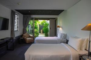 a hotel room with two beds and a television at The Pavilions Phuket in Bang Tao Beach