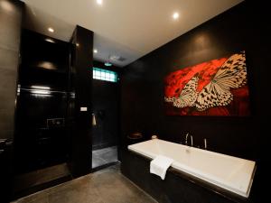 a bathroom with a tub and a painting on the wall at The Pavilions Phuket in Bang Tao Beach