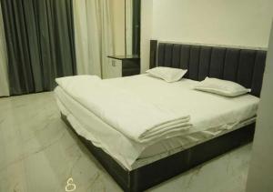 a bed with white sheets and pillows on it at Shri Hari Executive Lodge in Tuljapur