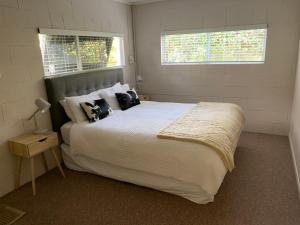 a bedroom with a large bed and two windows at Lake Views, Ani Miria Place, Te Rangiita, Turangi in Turangi