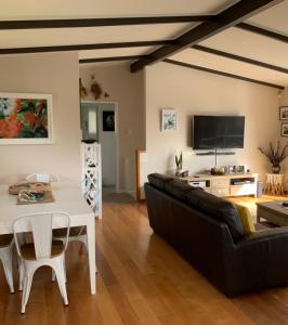 a living room with a black couch and a table at Lake Views, Ani Miria Place, Te Rangiita, Turangi in Turangi