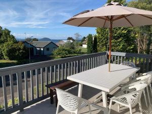 a white table and chairs with an umbrella on a balcony at Lake Views, Ani Miria Place, Te Rangiita, Turangi in Turangi