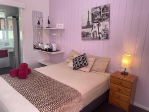a bedroom with a bed with a red stuffed animal on it at Taree Lodge Motel in Taree