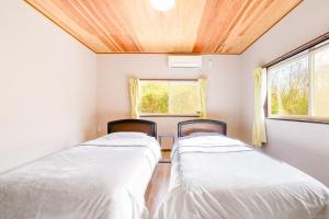two beds in a room with two windows at ウッドペッカーC棟BBQPetりんどう湖近くの一棟貸別荘 in Nasu